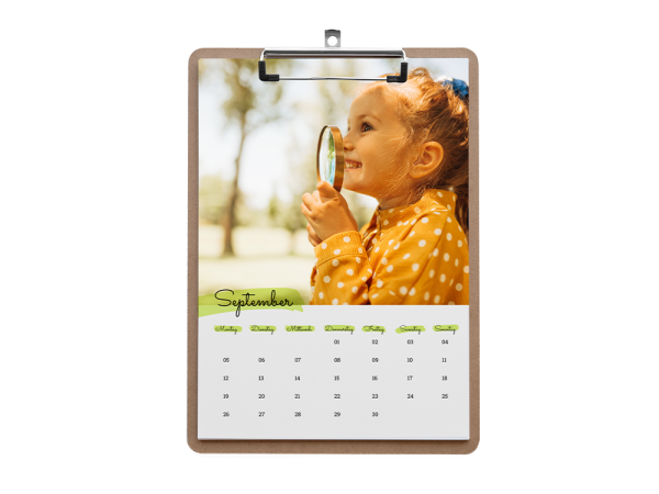 Ein Kind mit einer Lupe erkundet die Natur, abgebildet auf einem Klemmbrettkalender für den Monat September.